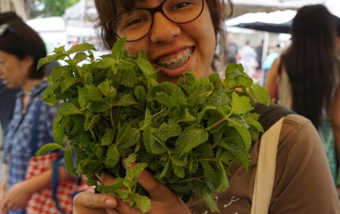 Woman smiles while holding a bunch of leaves.