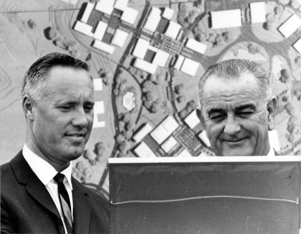 President Lyndon B. Johnson and another man looking at a sign with a campus map behind them